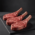 Bone-In Ribeye Cowboy Cut 18oz steaks on dark slate